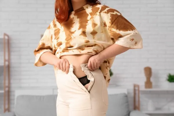 Image of woman trying to do her trousers up after pregnancy weight gain Rowley Regis
