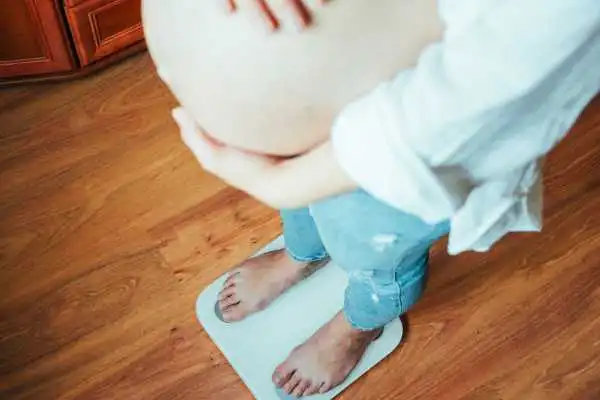 Image of woman weighing herself and experiencing weight gain through pregnancy Rowley Regis